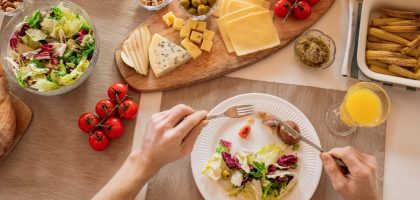 Overhead view of a cheese platter with fresh salad and juice, perfect for a gourmet lunch setting.
