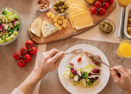 Overhead view of a cheese platter with fresh salad and juice, perfect for a gourmet lunch setting.