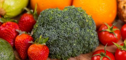 A vibrant collection of fresh, organic fruits and vegetables on a wooden table, showcasing healthy variety.