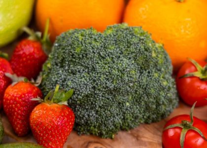 A vibrant collection of fresh, organic fruits and vegetables on a wooden table, showcasing healthy variety.